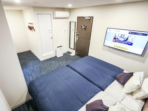 a bedroom with a blue bed and a flat screen tv at HOTEL LiVEMAX BUDGET Fuji Ekimae in Fuji