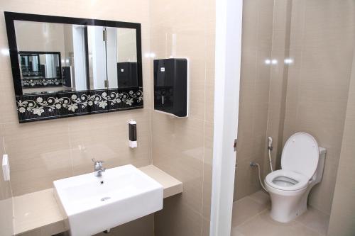 a bathroom with a toilet and a sink and a mirror at Arawa Traveller's Inn Motel in Makassar
