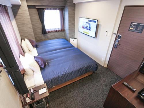 mały pokój z łóżkiem i drzwiami w obiekcie HOTEL LiVEMAX Tokyo Kanda-Ekimae w Tokio