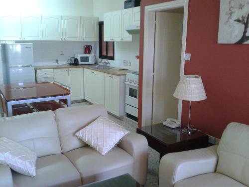 a living room with a white couch and a kitchen at Hill View Hotel Apartments in Pissouri