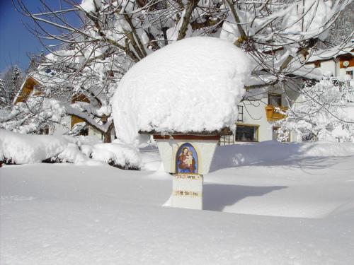 a bird feeder covered in snow in a yard at Bergheim Komfort Ferienwohnungen in Walchsee