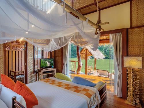 sypialnia z łóżkiem i dużym oknem w obiekcie The Float House River Kwai - SHA Extra Plus w mieście Sai Yok