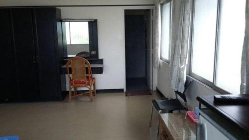 a room with a chair and a table and windows at Queen Songkhla Hotel in Songkhla