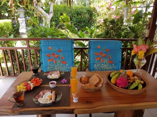 a wooden table with two plates of food on it at Dennis Holiday Bungalow in Jasri
