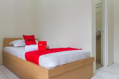 a bedroom with a bed with red pillows on it at RedDoorz near Universitas Siliwangi Tasikmalaya in Tasikmalaya
