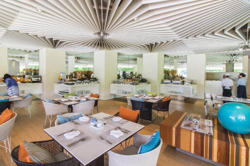 um restaurante com mesas e cadeiras e pessoas ao fundo em Veranda Resort Pattaya - MGallery Collection, Accor Hotel em Praia de Jomtien