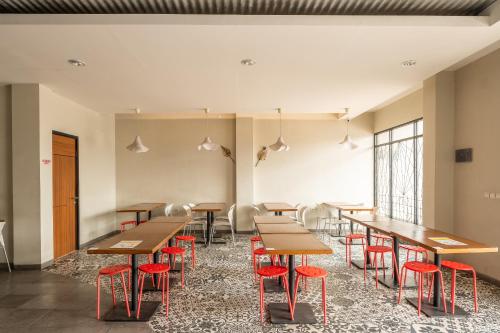 a cafeteria with wooden tables and red chairs at OYO 535 Cileunyi Residence Syariah in Bandung