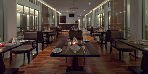 a restaurant with tables and chairs in a room at Vivanta Colombo, Airport Garden in Negombo