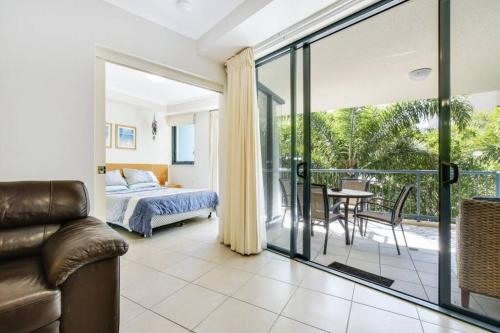 1 Schlafzimmer mit einem Bett und einem Balkon mit einem Tisch in der Unterkunft 1 Bedroom - Private Managed Oaks Resort - Pool and Beach - Alex in Maroochydore