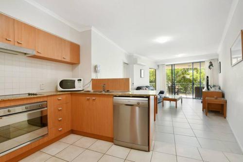 a kitchen with wooden cabinets and a living room at Beachside 1-Bedroom Apartment -Alex and Mooloolaba in Maroochydore