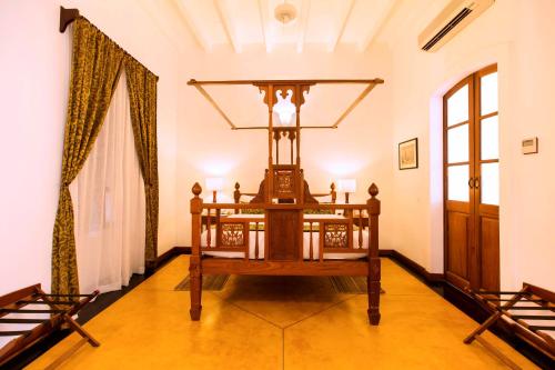a room with a bed in the middle of a room at Palais De Mahe - CGH Earth in Puducherry