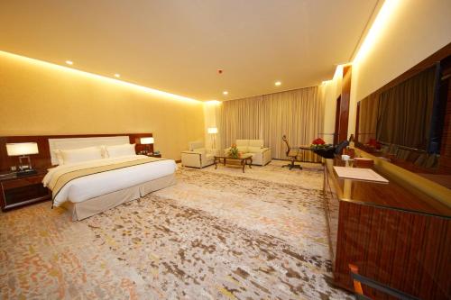 a large hotel room with a bed and a television at Royal Swiss Lahore in Lahore