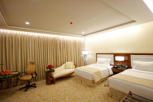 a hotel room with two beds and a chair at Royal Swiss Lahore in Lahore