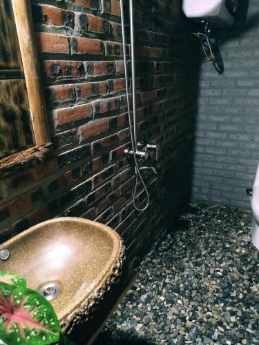 a bathroom with a copper sink next to a brick wall at Anh Duc Homestay in Sa Pa