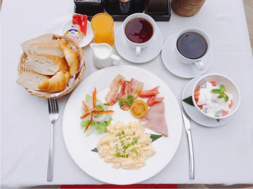a white table topped with plates of food and coffee at Home Indochine d'Angkor Hotel in Siem Reap