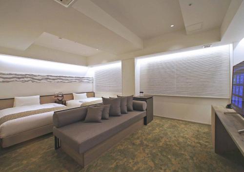a bedroom with a couch and a bed and a television at ORIENTAL HOTEL KYOTO ROKUJO in Kyoto