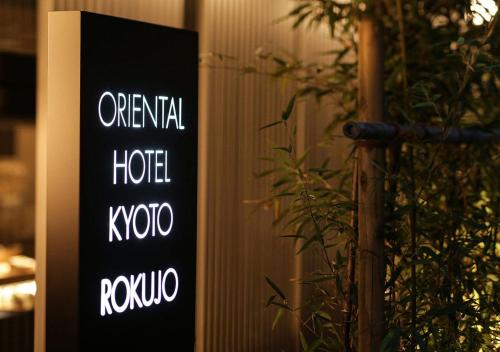ein Schild, auf dem der ursprüngliche Hotelkoko neben einer Pflanze steht in der Unterkunft ORIENTAL HOTEL KYOTO ROKUJO in Kyoto