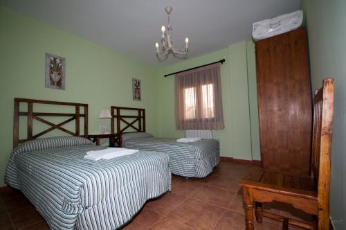 two beds in a room with green walls and a window at Alojamientos Rurales la Fuente in Villalba de la Sierra