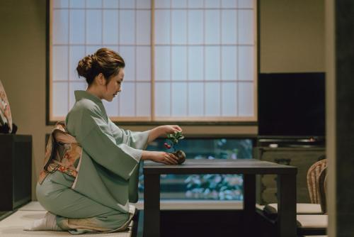京都市にある谷町君 星屋 大宮旅館 京都四条大宮の植物を抱いたテーブルに座る女