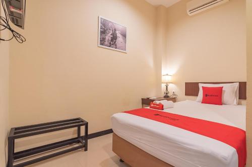 a bedroom with a large bed with a red blanket at RedDoorz at H Agus Salim Street Pontianak in Pontianak