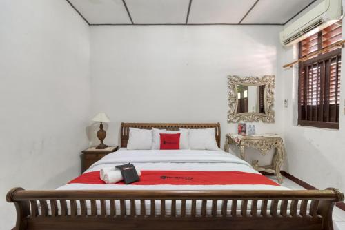 a bedroom with a large bed with a red blanket at RedDoorz Syariah near Wijilan 2 Yogyakarta in Yogyakarta