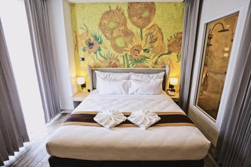 um quarto com uma cama grande e uma pintura na parede em Bright Hotel em Khon Kaen