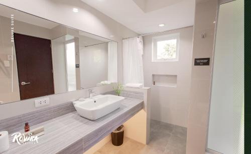 ein Badezimmer mit einem Waschbecken und einem großen Spiegel in der Unterkunft Rovira Suites in Dumaguete
