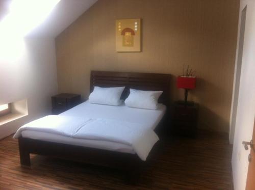 1 dormitorio con 1 cama con sábanas y almohadas blancas en Central Apartman Sopron, en Sopron