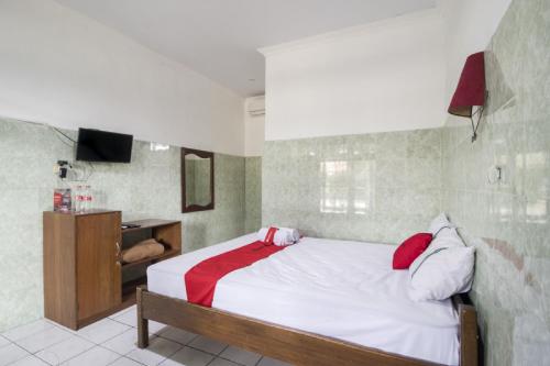 1 dormitorio con 1 cama con almohadas rojas y blancas en RedDoorz @ Sagan Jogja 2, en Yogyakarta