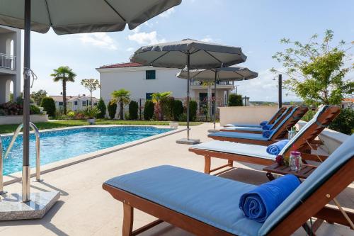 grupa leżaków i parasol przy basenie w obiekcie Deluxe Apartments Vila Carissa w mieście Malinska