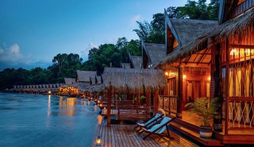 a resort on the water with chairs and buildings at The Float House River Kwai in Sai Yok