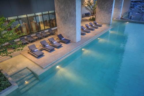 是拉差的住宿－Oakwood Hotel & Residence Sriracha - SHA Extra Plus，一个带躺椅的游泳池和一间酒店