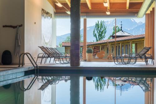a swimming pool with chairs next to a house at Hartungs Hoteldorf in Füssen