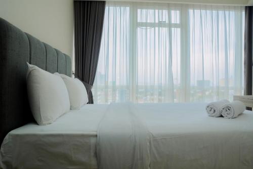 Un dormitorio con una cama grande con toallas. en Wonderful 2BR at Menteng Park Apartment By Travelio, en Yakarta