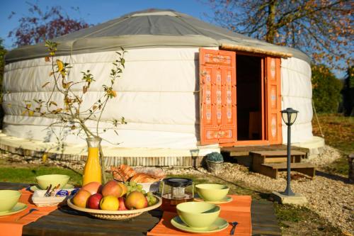 a table with a bowl of fruit in front of a yurt at Le Village des Templiers in Trie-Château