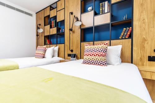 two beds in a room with wooden walls and shelves at Campanile Shanghai Huaihai in Shanghai