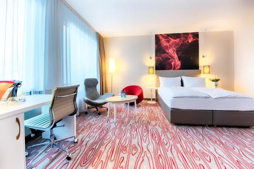 pokój hotelowy z łóżkiem, biurkiem i krzesłami w obiekcie ACHAT Hotel Bremen City w Bremie