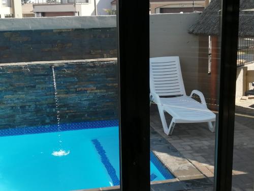 a view of a swimming pool from a window with a chair at Sunflower Guesthouse in Vanderbijlpark