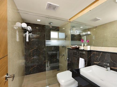 a bathroom with a toilet and a sink and a shower at Flora Charishma Residency Aluva in Cochin
