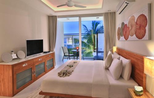 a bedroom with a bed with a television and a balcony at Chi Samui Resort in Bophut