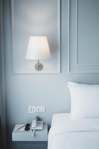 a lamp on a table next to a bed at The Wing Boutique Hotel in Chiang Mai