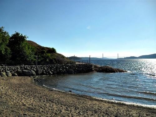 a beach with rocks and water with a bridge in the background at Gustafsbergs Badhotell & Vandrarhem in Uddevalla