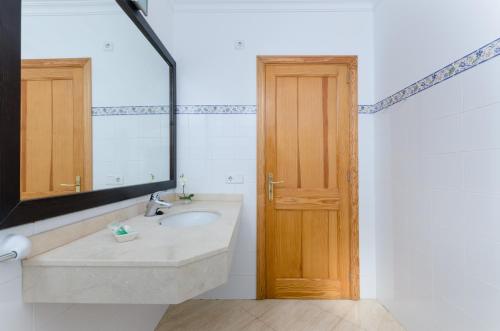 een badkamer met een wastafel, een spiegel en een deur bij Bexan Cala Mandia in Cala Mendia