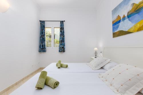 een witte slaapkamer met 2 bedden en een raam bij Bexan Cala Mandia in Cala Mendia