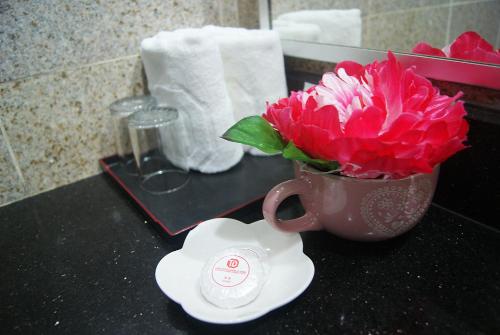 a pink flower in a cup on a bathroom counter at TD Plaza Hotel in Kota Kinabalu