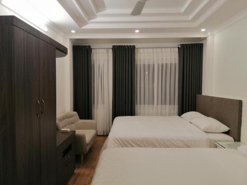 a hotel room with two beds and a chair at Sao Mai Cosy Nest-Noi Bai Airport in Thach Loi