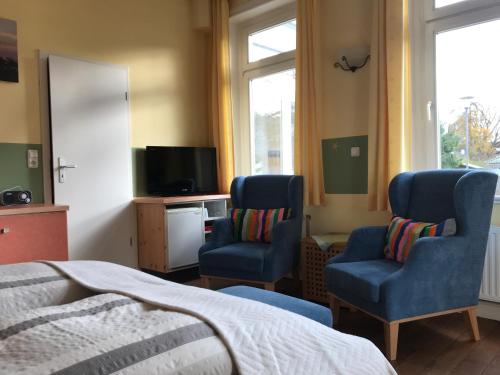 ティメンドルファー・シュトラントにあるVilla Möwensteinのベッドルーム1室(椅子2脚、ベッド1台、テレビ付)