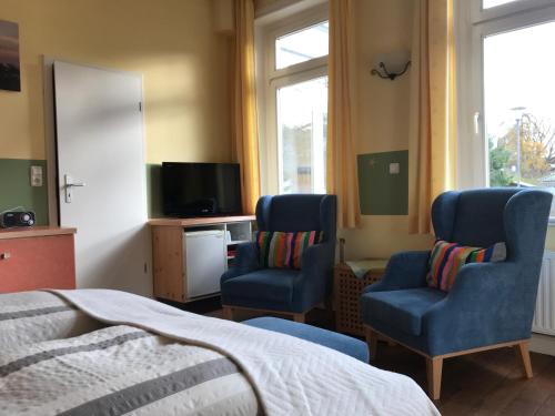 1 dormitorio con 2 sillas, 1 cama y TV en Villa Möwenstein, en Timmendorfer Strand