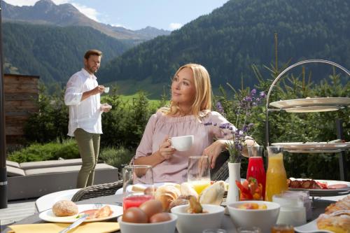 a man and a woman sitting at a table with food at Chalet SALENA luxury lodge in Santa Maddalena in Casies