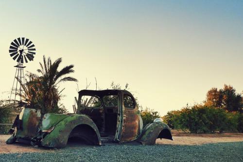 an old truck sitting on the ground next to a windmill at Vastrap Guest Farm in Grünau